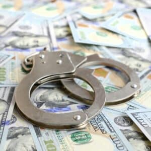 Silver police handcuffs lies on a many dollar bills.